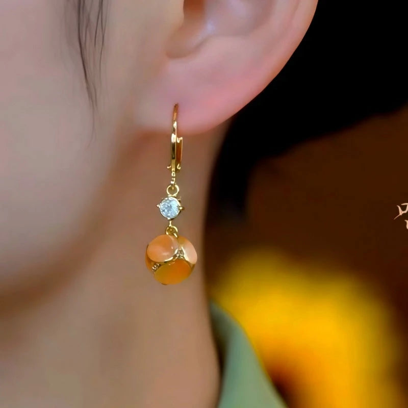 Model showcasing the dangle and style of the 14K Gold-Plated Elegant Zircon Brown Cat's Eye Stone Earrings