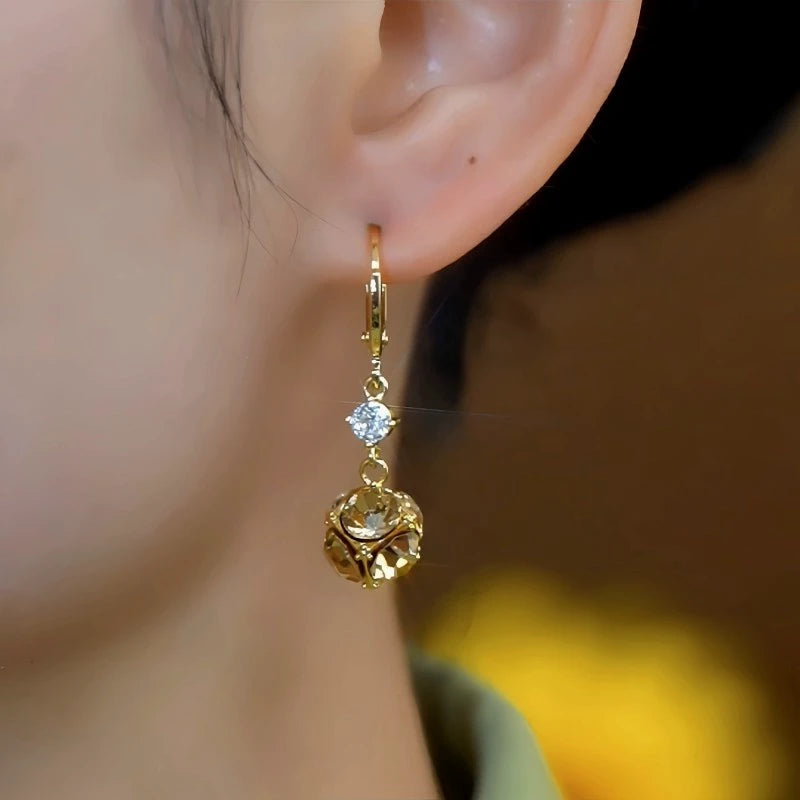 Model showcasing the dangle and style of the 14K Gold-Plated Elegant Zircon Brown Diamond Ball Earrings