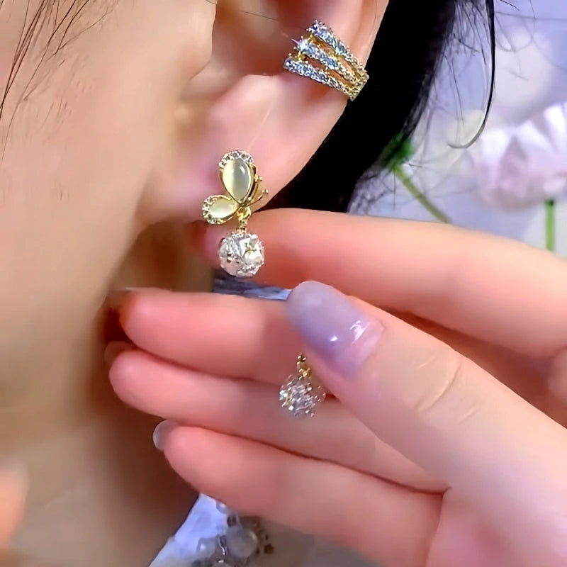 Model showcasing the dangle and style of the 14K Gold-Plated Elegant Zircon Cat's Eye Stone Butterfly Ball Earrings