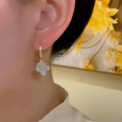 Model showcasing the dangle and style of the 14K Gold-Plated Elegant Zircon Four-Leaf Flower Earrings