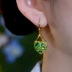 Model showcasing the dangle and style of the 14K Gold-Plated Elegant Zircon Green Diamond Heart Earrings