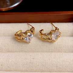 Close-up detail of the sparkling zircons and plating on the gold heart earrings