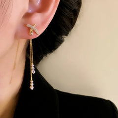 Model showcasing the dangle and style of the 14K Gold-Plated Elegant Zircon X Cross Tassel Earrings