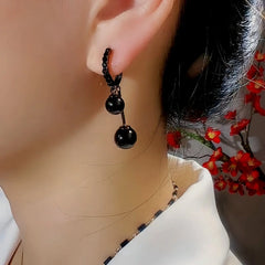 Model showcasing the dangle and style of the 14K Gold-Plated Exquisite Black Ball Pearl Earrings