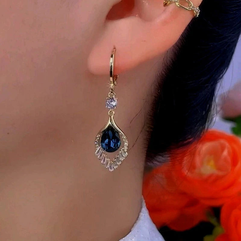 Model showcasing the dangle and style of the 14K Gold-Plated Exquisite Blue Peacock Tail Earrings
