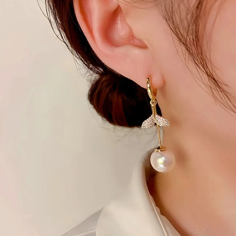 Model showcasing the dangle and style of the 14K Gold-Plated Exquisite Diamond-Filled Fishtail Pearl Tassel Earrings