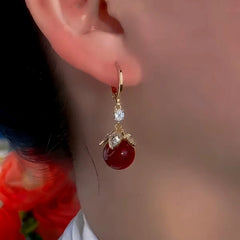 Model showcasing the dangle and style of the 14K Gold-Plated Exquisite Red Bead Earrings