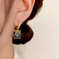 Model showcasing the dangle and style of the 14K Gold-Plated Exquisite Square Diamond Bow Zircon Earrings