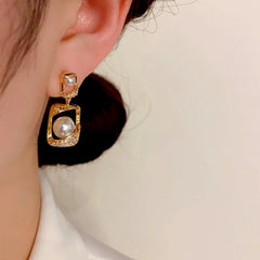 Model showcasing the dangle and style of the 14K Gold-Plated Geometric Pearl Earrings