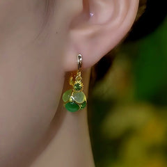 Model showcasing the dangle and style of the 14K Gold-Plated Green Cat's Eye Stone Ball Tassel Earrings