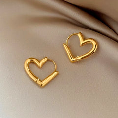 Model showcasing the dangle and style of the 14K Gold-Plated Hollow Heart Earrings