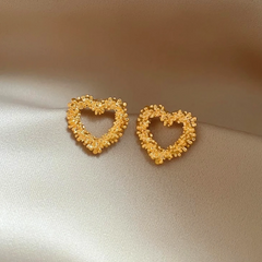 Model showcasing the dangle and style of the 14K Gold-Plated Hollow Heart Stud Earrings