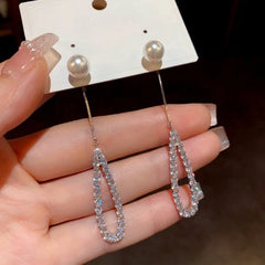 Model showcasing the dangle and style of the 14K Gold-Plated Hollow Pearl Diamond Tassel Earrings