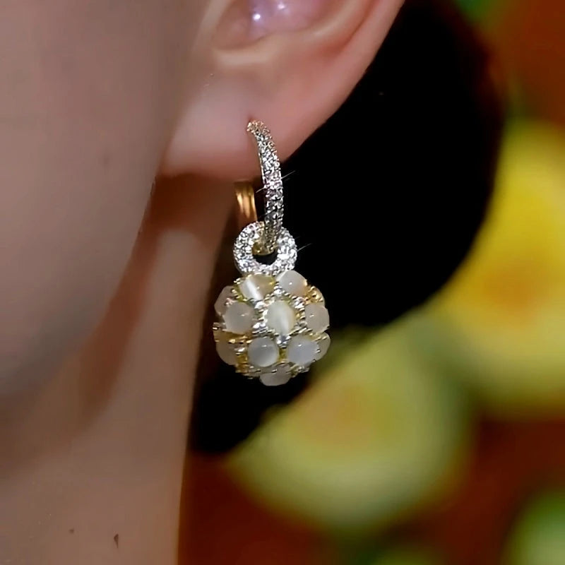 Model showcasing the dangle and style of the 14K Gold-Plated Luxury Cat's Eye Ball Earrings