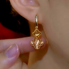 Model showcasing the dangle and style of the 14K Gold-Plated Luxury Cat's Eye Four-Leaf Flower Earrings