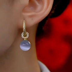 Model showcasing the dangle and style of the 14K Gold-Plated Luxury Cat's Eye Stone Ball Earrings