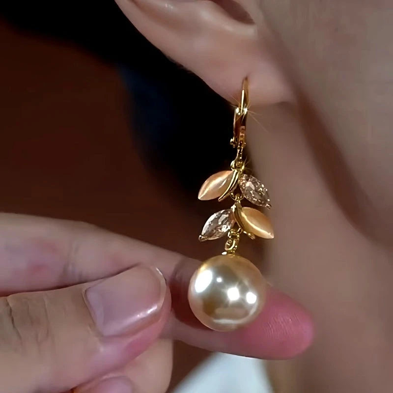 Model showcasing the dangle and style of the 14K Gold-Plated Luxury Cat's Eye Stone Leaf Pearl Earrings