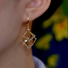 Model showcasing the dangle and style of the 14K Gold-Plated Luxury Geometric Diamond Brown Crystal Earrings
