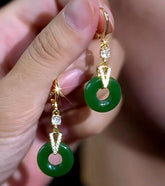 Hand holding pair of gold-tone green jade donut drop earrings with CZ accents