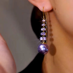 Model showcasing the dangle and style of the 14K Gold-Plated Luxury Purple Zircon Pearl Threader Tassel Earrings