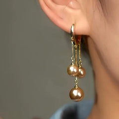 Model showcasing the dangle and style of the 14K Gold-Plated Luxury Three Champagne Gold Pearl Tassel Earrings