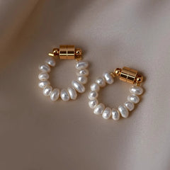 Pair of freshwater pearl hoop earrings with gold magnetic clasp on beige satin