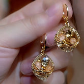 Pair of gold hollow square champagne crystal drop earrings held in hand