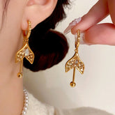 Gold Champagne Crystal Mermaid Tail Dangle Earrings: One Worn, One Held by Hand