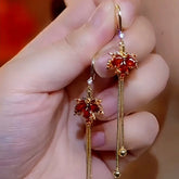Pair of red maple leaf gold tassel long dangle earrings held in hand