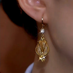 Side closeup of gold teardrop crystal dangle earring worn on ear