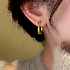Close-up of gold bamboo square hoop earring on a woman's ear