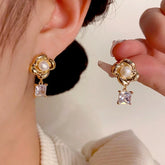 Gold flower pearl square crystal drop earrings: one worn on ear, one held by hand