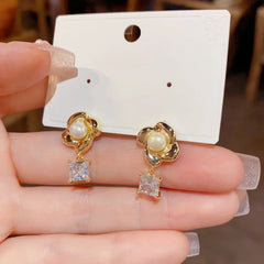 Pair of gold flower pearl square crystal drop earrings on earring display card