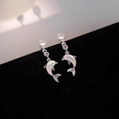 Pair of silver pearl dolphin drop earrings on black velvet display