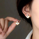 Gold mother of pearl heart stud earrings with pearl accent, woman wearing one and holding another