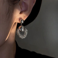 Close-up of silver crescent drop earring worn on ear
