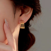 Gold triple hoop teardrop dangle earring worn on woman's earlobe