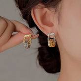 Asymmetric gold silver two-tone layered square hoop earrings, one worn on ear, one held in hand