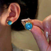 Gold bezel veined turquoise stud earring held by hand, matching worn earring in background