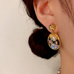 Model showcasing the dangle and style of the 14K Gold-Plated Oil-Dripping Freshwater Pearl Flower Oval Earrings
