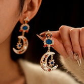 Vintage enamel moon star pearl drop earrings, woman wears one and holds the other