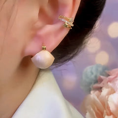 Pearlescent cream teardrop stud earring worn on ear with gold star ear cuff