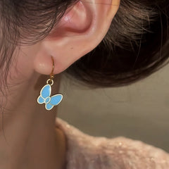 Model showcasing the dangle and style of the 14K Gold-Plated Oil Drop Blue Butterfly Ear Hooks