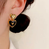 Gold hammered black enamel double heart drop earring worn on woman's ear