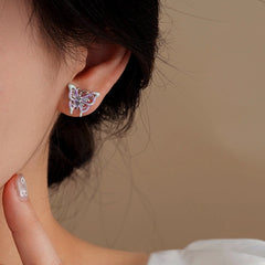 Closeup of purple enamel butterfly stud earring worn on woman's ear