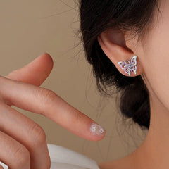 Purple mint enamel butterfly stud earring worn on ear, hand with nail art nearby