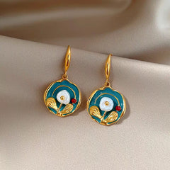 Teal enamel gold floral drop earrings with pearl on folded beige satin
