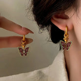 Vintage gold red enamel butterfly drop hoop earrings, hand held beside worn earring