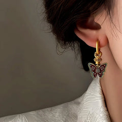 Detailed side view of gold enamel butterfly drop hoop earring on ear