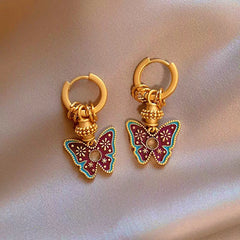Vintage boho gold hoop earrings with purple enamel butterfly pendants on satin fabric
